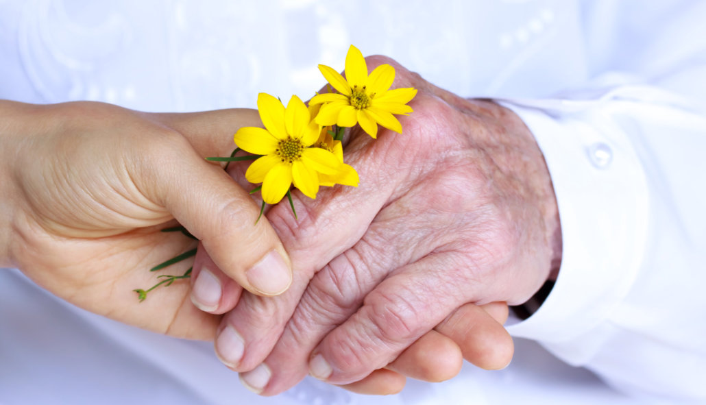 caregiver and old woman holding a flower